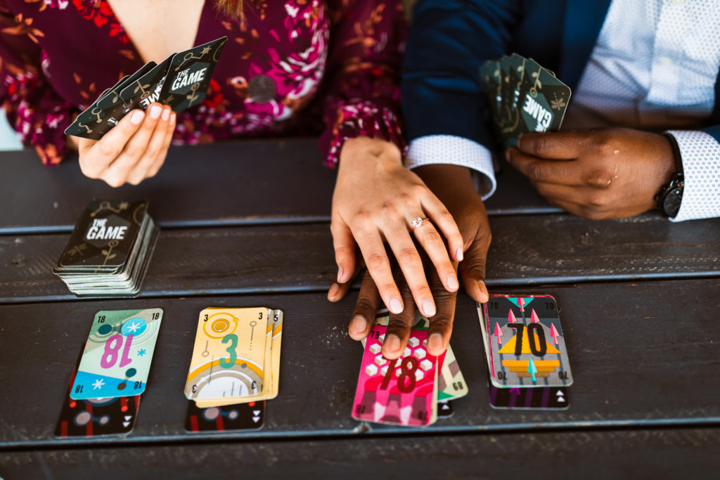 Couple playing cards "The Game" by Pandasaurus Games at Whiskey Bird in Midtown Atlanta Georgia | Engagement ring by Brilliant Earth | Photo by Meli and Chris Wedding Photography