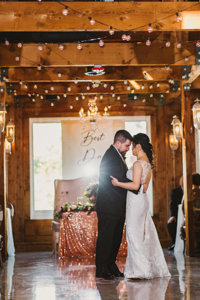 Couple dancing at wedding reception area with shiny floor and wooden walls inside the Cotton Gin at Mill Creek.. Photo by Meli and Chris Wedding Photography atlweddingphotos.com