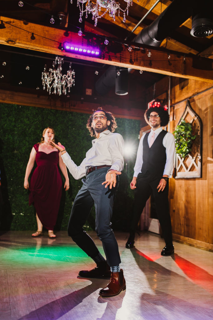 Three people dancing under DJ lights during wedding reception at Cotton Gin at Mill Creek.