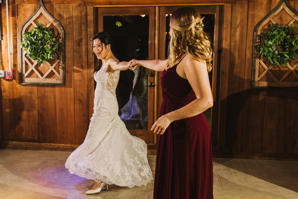 Bride and bridesmaid dancing during wedding reception at Cotton Gin at Mill Creek.