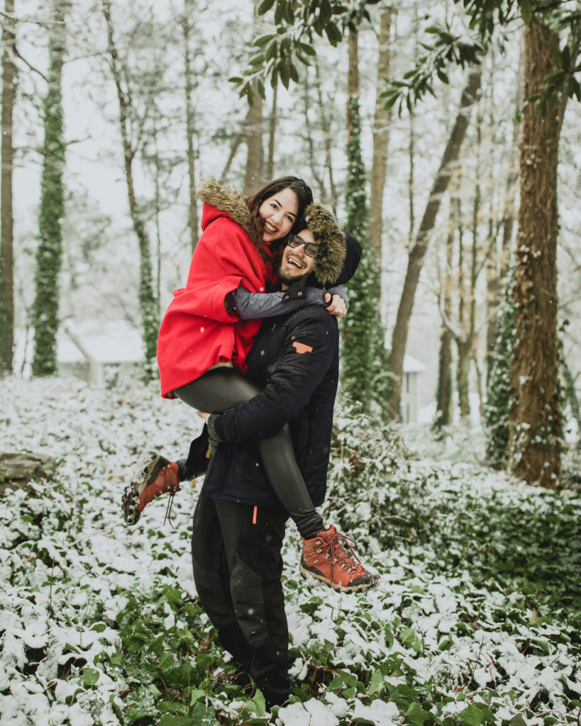 A woman with a red coat hanging out with a man with a blue jacket  at a snowy place | Photo by Meli and Chris Atlanta Based destination Wedding Photography.